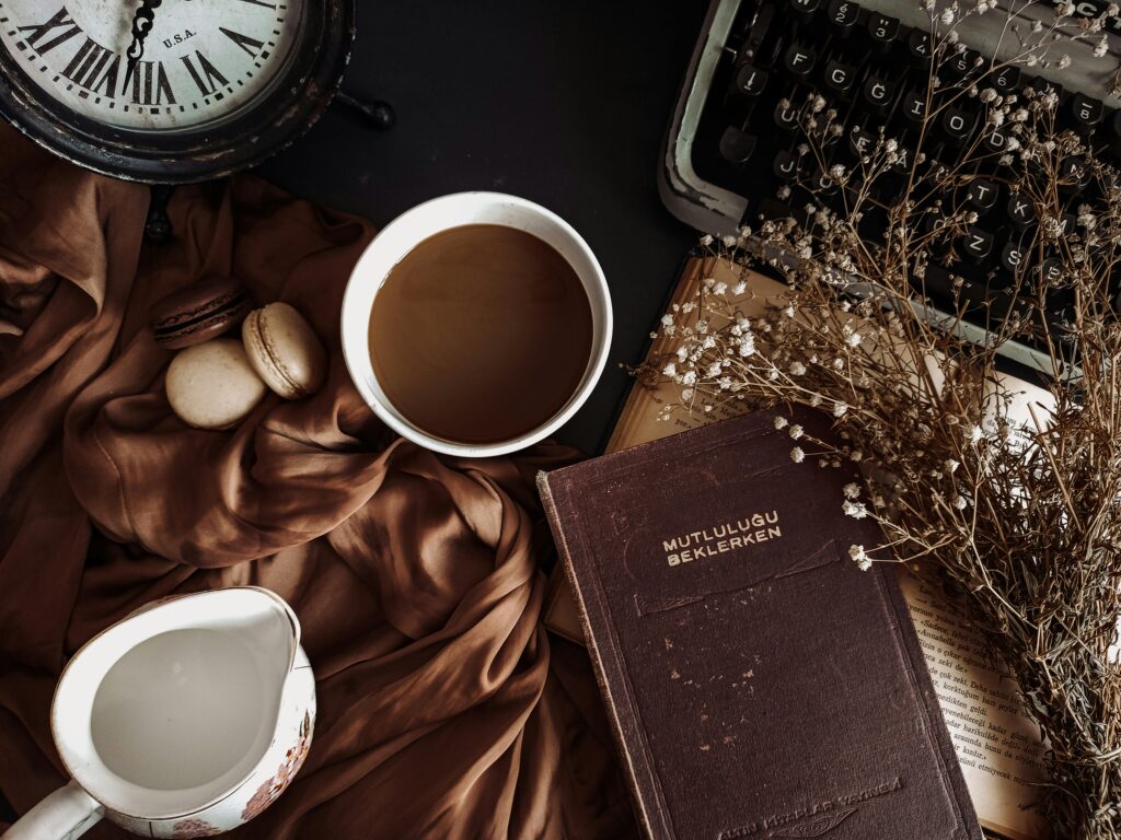 Aesthetic flat lay with coffee, book, typewriter, and rustic elements creating a vintage atmosphere.